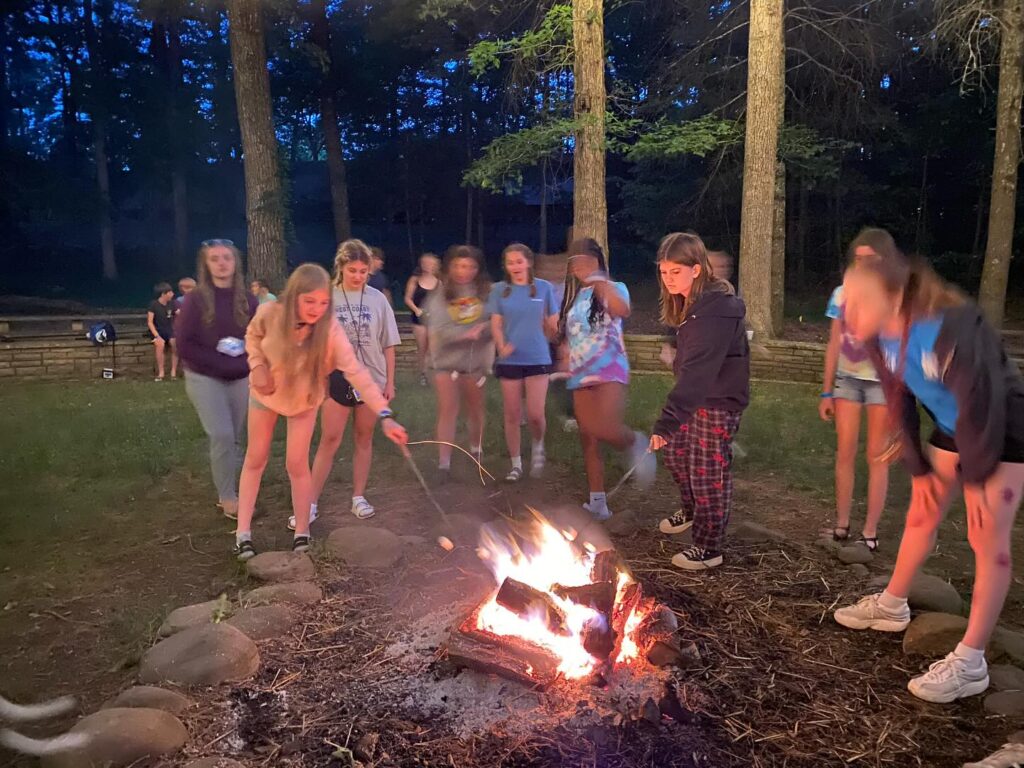 Youth roasting marshmallows over a fire.