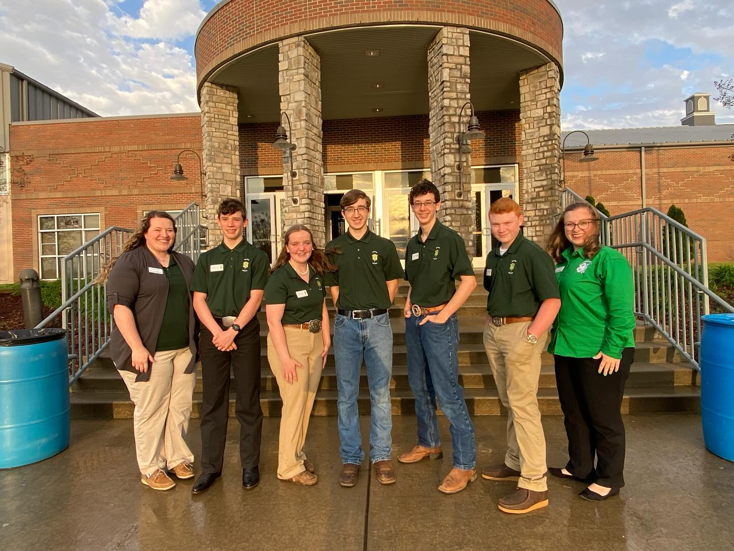 Youth standing in front of a building.  All are wearing green 4-H shirts. 