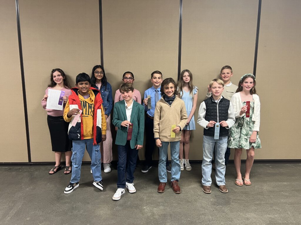 Youth smiling and holding 4-H ribbons