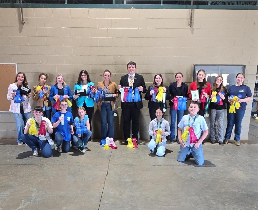 Youth in the horse arena showing off ribbons and plaques from a 4-H Horse competition. 