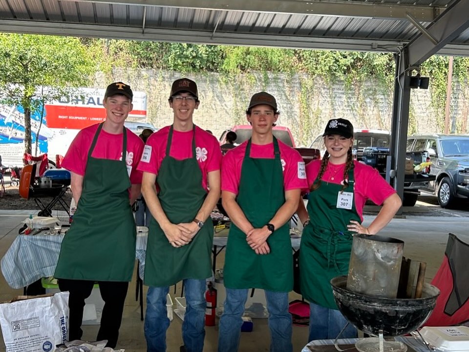 Senior High 4-H Grill Master Team members lined up wearing green aprons and red shirts.