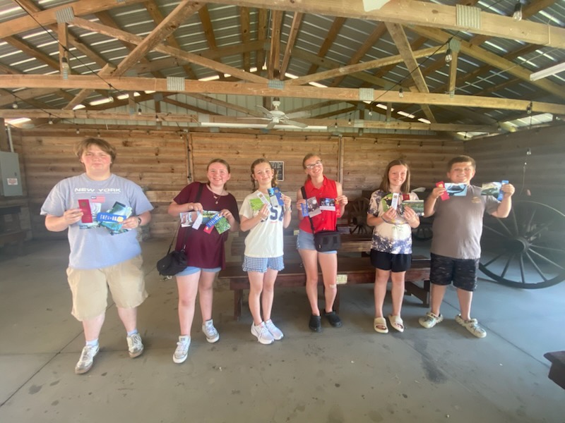 6 youth standing in a row holding photos and ribbons